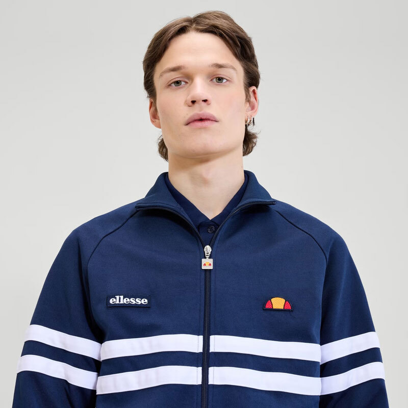 Close up photo of model wearing blue Ellesse track top